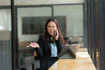 Wall Mural - Asian woman talking on smartphone with customer Business matters