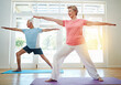 © GR/peopleimages.com - Yoga, stretching and mature couple in home for fitness, health and wellness with warrior pose. Workout, senior man and woman on mat for pilates, balance and body care exercise together in retirement.