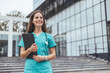 © Dragana Gordic - A cheerful Caucasian woman in scrubs holds a clipboard, displaying professionalism and readiness near a hospital setting.