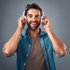 Poster - Portrait, man and headphone for hands in studio, audio media and podcast or ebook on gray background. Technology, streaming and music subscription for song, male person and smile for listening