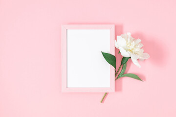 Flower composition with peonies. Blank photo frame with white peonies on pastel pink background. Birthday, Wedding, Mother's Day, Valentine's day, Women's Day. Flat lay, top view, copy space