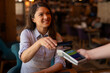 © Dexon Dee - Woman paying contactless with her smartphone in coffeehouse