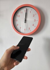 Man holding phone against the clocks, time flow, tapping screen