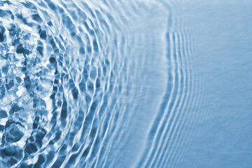 Wall Mural - Rippled surface of clear water on light blue background, closeup