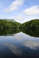 Un lago precioso entre montañas con reflejo en el agua de las nubes