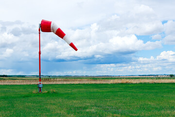 Weather vane in the airfield with grass and dramatic cloudy sky.