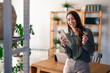 © Dorde - Happy young woman holding credit card using cell phone mobile app paying online making purchase in e-commerce digital store on smartphone at home. Virtual shopping, secure mobile banking concept.