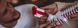 © ArtSys - Banner. Happy loving young beautiful couple exchanging gift boxes for Christmas, new year or saint Valentine's Day. Man and woman in casual clothes holding presents, smiling, enjoying holidays at home