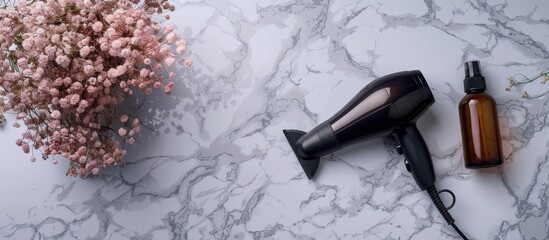 black hair dryer and spray bottle with flowers on marble background, top view flat lay. hairdressing