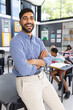 © Wavebreak Media - Young Asian male teacher with a beard smiles confidently in a school classroom