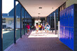 © Wavebreak Media - Excited children are running through a school corridor, lockers lining the wall with copy space