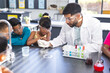 © Wavebreak Media - Young Asian male teacher conducts a science experiment with diverse children in school