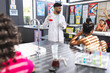 © Wavebreak Media - Young Asian male teacher in a lab coat demonstrates a science experiment to students in school