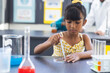 © Wavebreak Media - Biracial girl in a yellow dress is conducting a science experiment in school