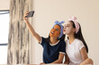 © Wavebreak Media - Two biracial young sisters at home, taking selfie with a smartphone, in face masks