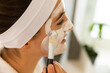 © Wavebreak Media - At home, young Caucasian woman applying facial mask with brush in modern home spa