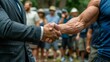 © Mikus - A close-up of two people shaking hands, one in a suit and tie, amidst a crowd of people in blue shirts and hats