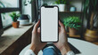 © MariКа - female hands using smartphone in the living room with white blank screen display mockup