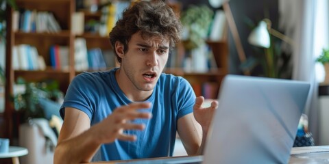Young man in a blue shirt feeling frustrated while using a laptop