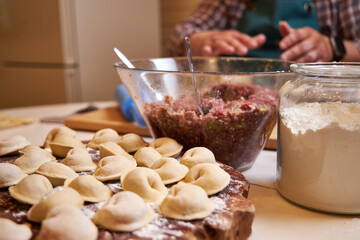 family at the table in the kitchen making dumplings