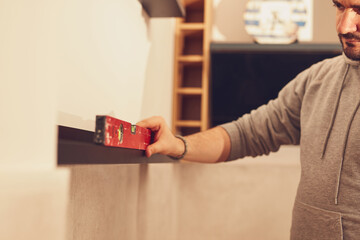 Wall Mural - Handyman with sprit level checking a small shelf hanged on the wall.