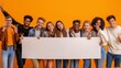 © YURIMA - A diverse group of young friends happily holding a blank sign against an orange background, depicting unity, friendship, and support amongst a vibrant community of multiethnic peers