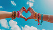 © MuhammadQaiser - Hands making heart symbol on sky background. friendship bracelets on wrists