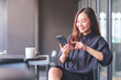 © Farknot Architect - Portrait image of a young woman holding and using mobile phone in cafe