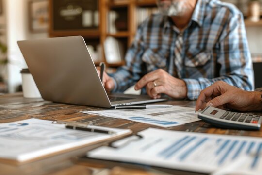 A close-up image of a financial advisor assisting a middle-aged client with tax planning. The advisor uses a laptop to present detailed information while the client follows along, holding a