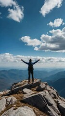 Wall Mural - A lone person stands on top of a big mountain with hands towards the sky as to celebrate their achievement