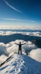 Wall Mural - A lone person stands on top of a big mountain with hands towards the sky as to celebrate their achievement