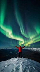 Wall Mural - A lone person stands on top of a big mountain with hands towards the sky as to celebrate their achievement