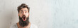© Nataliia_Trushchenko - A man with a beard and a surprised expression on his face. The man is looking at the camera. a bearded male with his mouth open shocked and standing in front of an old white wall stock image