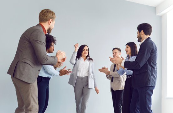 Multinational happy office business team, group applauding to colleague, celebrating her success during a work meeting. Teamwork and support, positive and encouraging work environment.