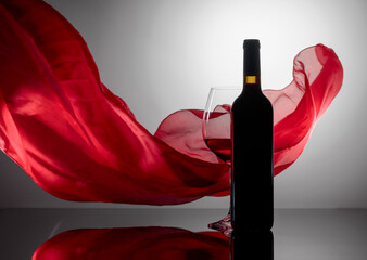 Wall Mural - Bottle and glass of red wine on a black reflective background.