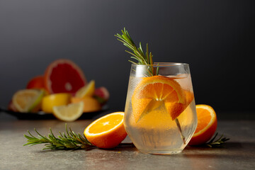 Poster - Cocktail gin tonic with ice, rosemary, and orange on a stone table.