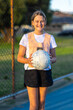 © Austockphoto - netball player holding ball and smiling looking at camera