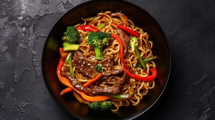 Wall Mural - Black bowl filled with stir-fried noodles, vibrant vegetables, and succulent beef
