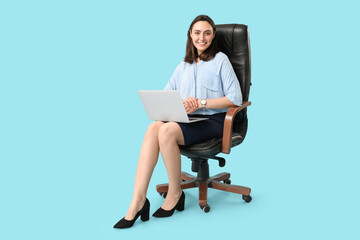 Wall Mural - Young businesswoman with laptop sitting on chair on blue background