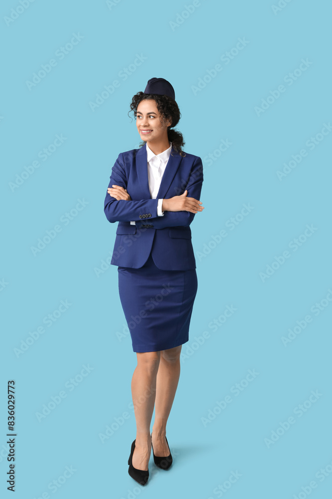 Beautiful African-American stewardess on blue background