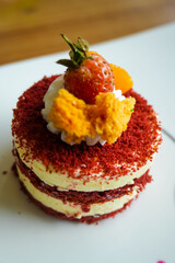 Red velvet cake, classic three layered cake from red butter sponge cakes with cream cheese frosting, with mandarin orange and candied strawberry as topping American cuisine