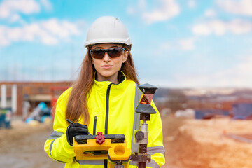 Dedicated happy smiling female civil engineer surveyor working with surveying tools