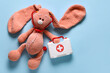 © Pixel-Shot - Toy first aid kit and toy bunny on blue background. Top view
