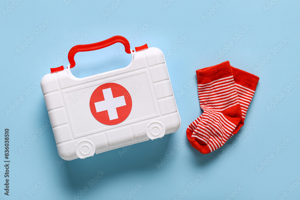 Toy first aid kit with kid's socks on blue background. Top view