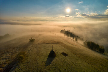 Wall Mural - Fog spreads over the mountains at dawn. The sun rises on the horizon. Carpathians in the morning. Aerial drone view.