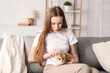 © Pixel-Shot - Young woman stroking cute kitten on sofa at home