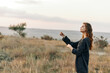 © VICHIZH - Woman standing in open field with outstretched arms gazing up at the sky in awe