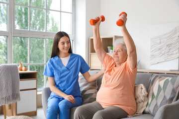 Wall Mural - Young nurse and senior woman with dumbbells training at home