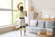 © Pixel-Shot - Sporty African-American woman with laptop and resistance band exercising at home
