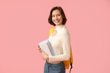 Wall Mural - Beautiful female student with backpack and books on pink background